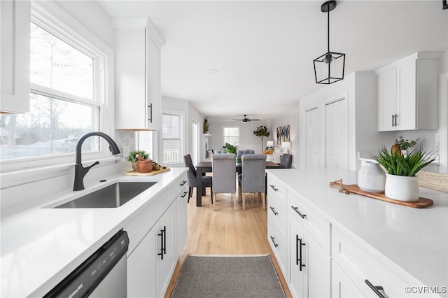 kitchen with pendant lighting, sink, stainless steel dishwasher, and white cabinets