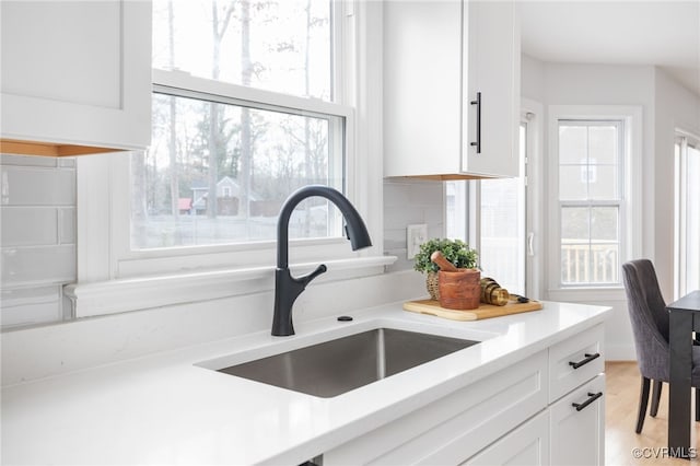 room details with tasteful backsplash, sink, and white cabinets