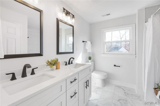 bathroom featuring vanity, a wealth of natural light, and toilet