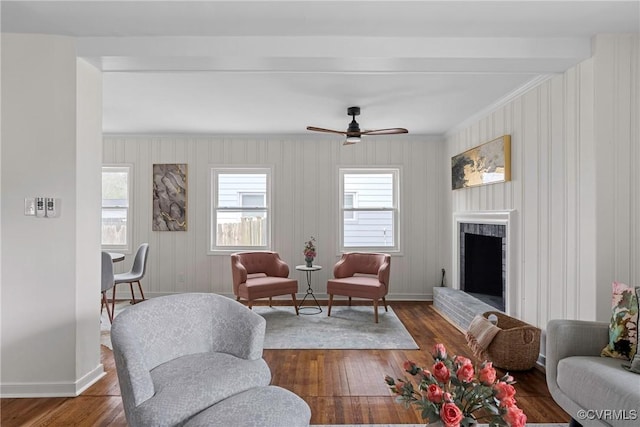 living room with ornamental molding, a brick fireplace, dark wood-type flooring, and ceiling fan