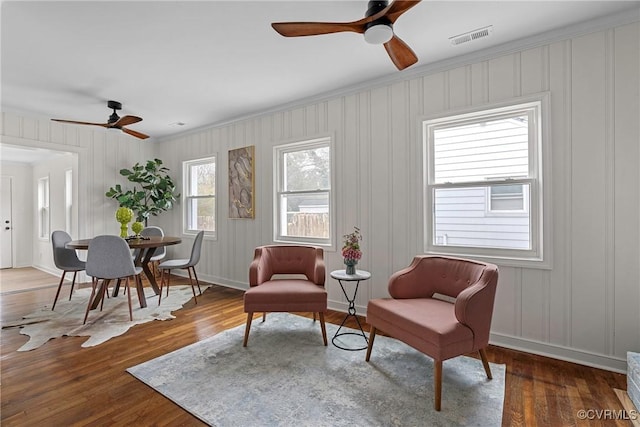 sitting room with wood-type flooring, ornamental molding, and ceiling fan