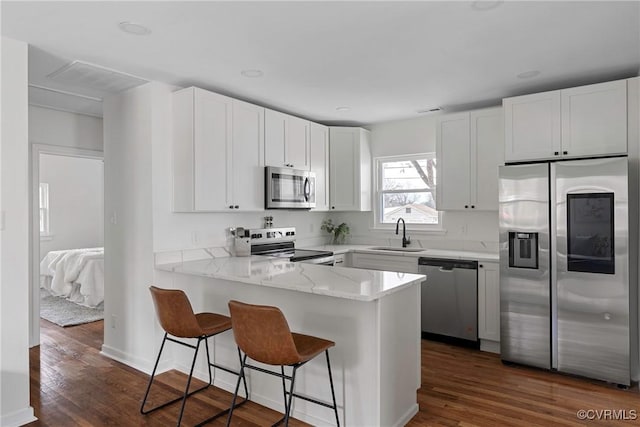 kitchen featuring stainless steel appliances, kitchen peninsula, and white cabinets