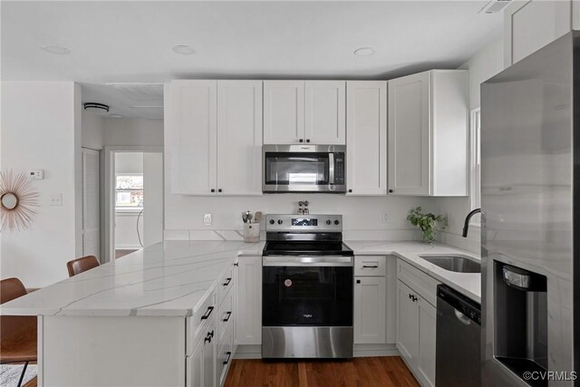 kitchen featuring white cabinetry, stainless steel appliances, a kitchen bar, and kitchen peninsula