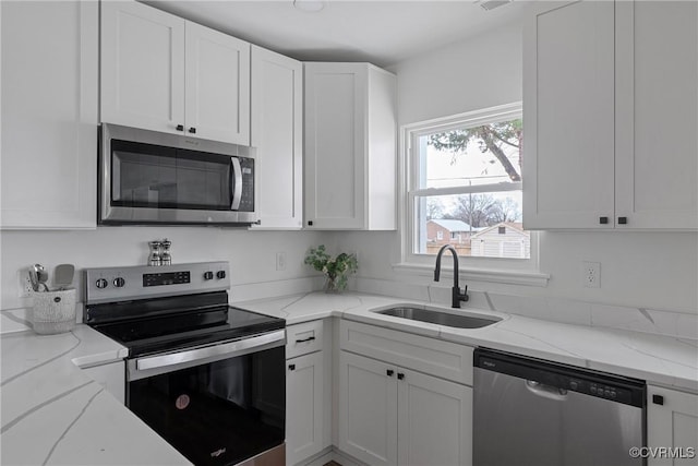 kitchen with stainless steel appliances, light stone countertops, sink, and white cabinets