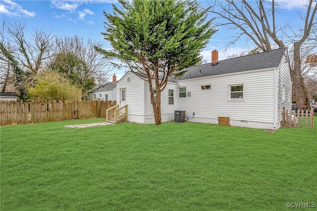 rear view of property with a lawn and central air condition unit