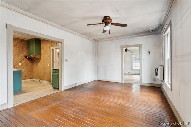 unfurnished room featuring wood walls, ornamental molding, heating unit, and light hardwood / wood-style flooring