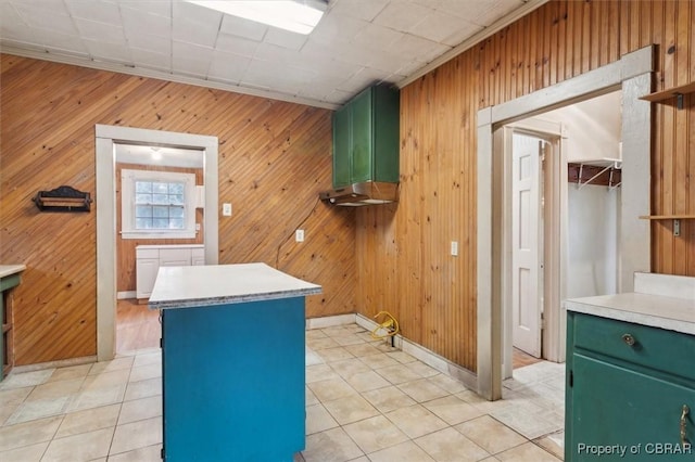 kitchen with green cabinets, light tile patterned floors, and wood walls