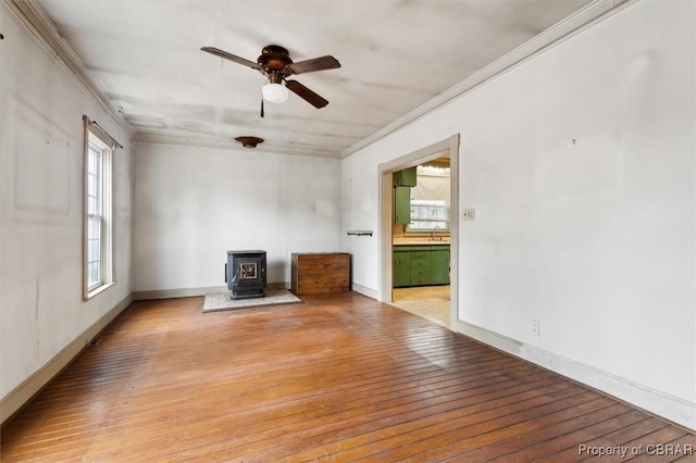 spare room featuring sink, crown molding, light wood-type flooring, and a wood stove