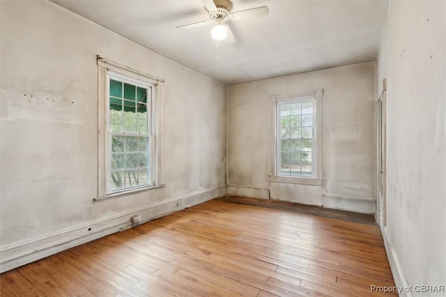 empty room with ceiling fan, a healthy amount of sunlight, and light hardwood / wood-style flooring