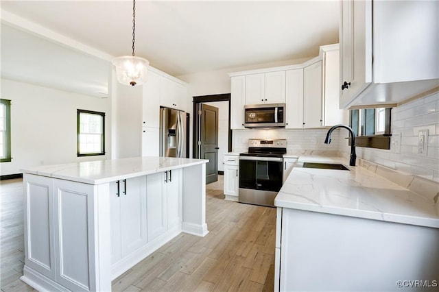 kitchen with sink, stainless steel appliances, a center island, white cabinets, and decorative light fixtures