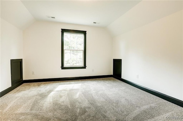 bonus room with lofted ceiling and light carpet