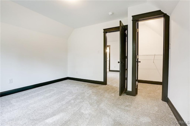 unfurnished room featuring vaulted ceiling and light colored carpet