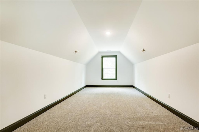 bonus room featuring vaulted ceiling and light carpet