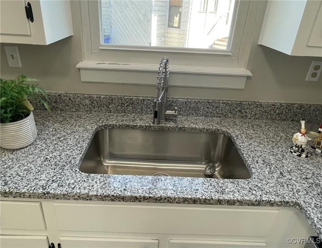 details with light stone countertops, sink, and white cabinets