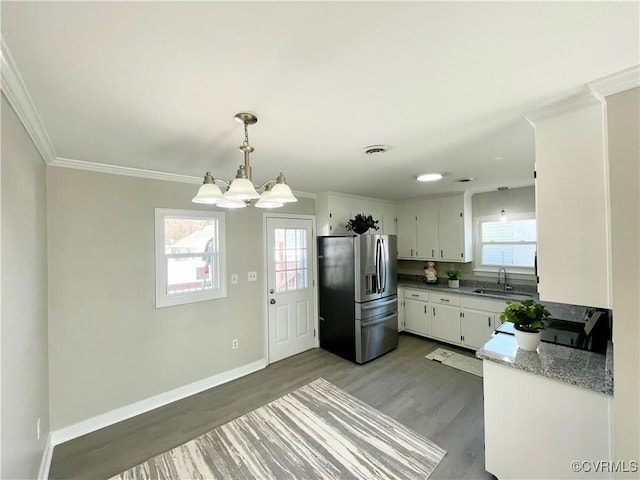 kitchen featuring stainless steel refrigerator with ice dispenser, sink, white cabinetry, hanging light fixtures, and ornamental molding