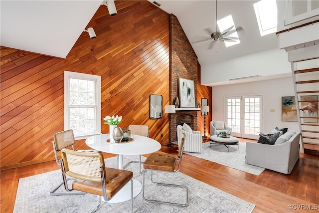 dining room featuring hardwood / wood-style floors, a fireplace, high vaulted ceiling, and ceiling fan