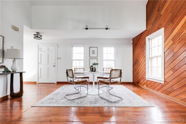 living area featuring a towering ceiling, wooden walls, and hardwood / wood-style floors