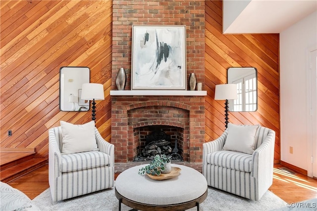 living area with light hardwood / wood-style flooring, a fireplace, and wood walls