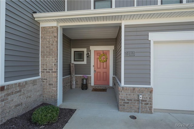 doorway to property featuring brick siding and a garage