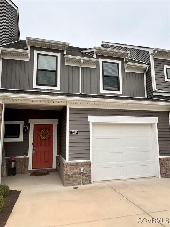 townhome / multi-family property featuring concrete driveway, central air condition unit, an attached garage, and board and batten siding