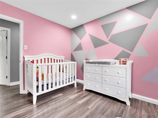 bedroom with hardwood / wood-style flooring and a crib