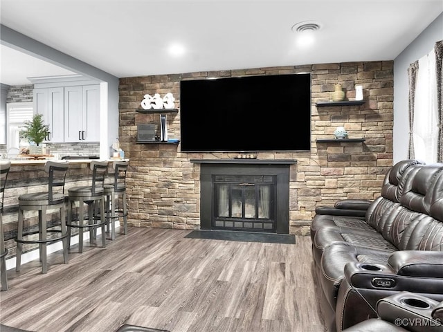 living room featuring a stone fireplace and light wood-type flooring