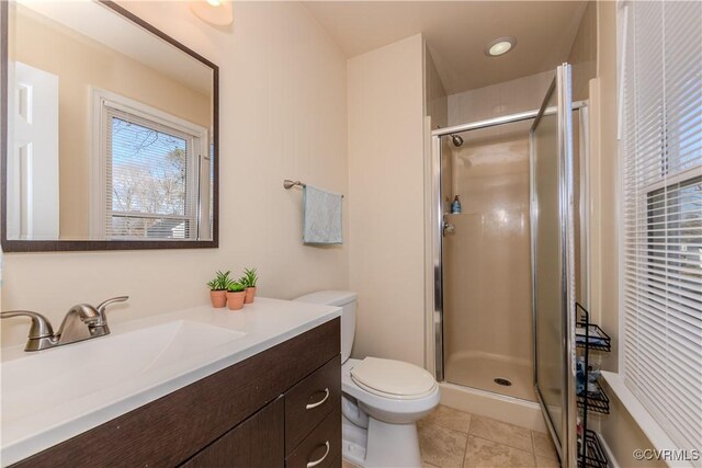 bathroom featuring tile patterned flooring, toilet, vanity, and walk in shower