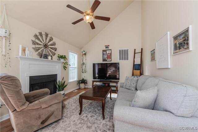 living room with ceiling fan, high vaulted ceiling, and light hardwood / wood-style floors