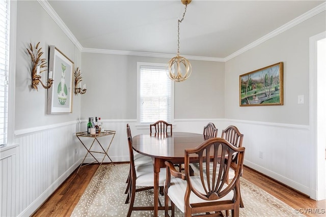 dining space with crown molding, a notable chandelier, and hardwood / wood-style flooring