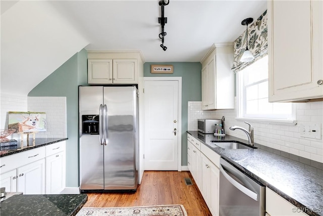 kitchen featuring tasteful backsplash, sink, hanging light fixtures, light hardwood / wood-style floors, and stainless steel appliances