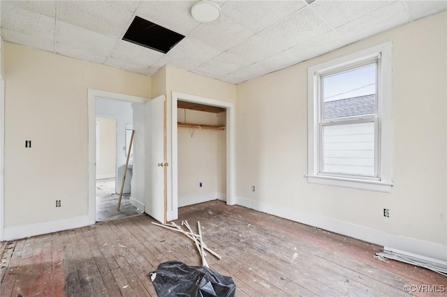 unfurnished bedroom featuring hardwood / wood-style floors, a closet, and a drop ceiling