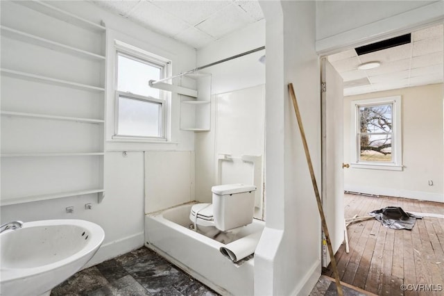 full bathroom with wood-type flooring, tub / shower combination, a healthy amount of sunlight, and toilet