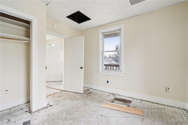 unfurnished bedroom with a paneled ceiling and a closet