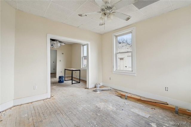 spare room featuring ceiling fan, light hardwood / wood-style flooring, and a drop ceiling