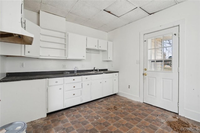 kitchen with sink, a drop ceiling, and white cabinets