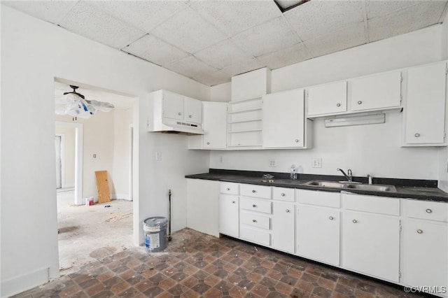 kitchen featuring a paneled ceiling, sink, and white cabinets