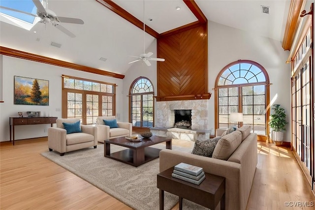 living area with high vaulted ceiling, a fireplace, light wood-style flooring, and a ceiling fan