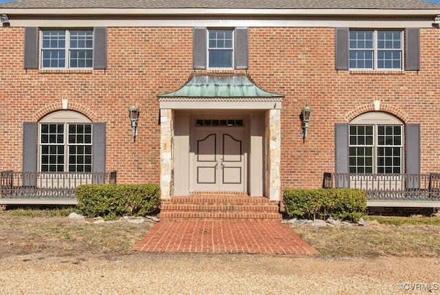 property entrance with brick siding and roof with shingles