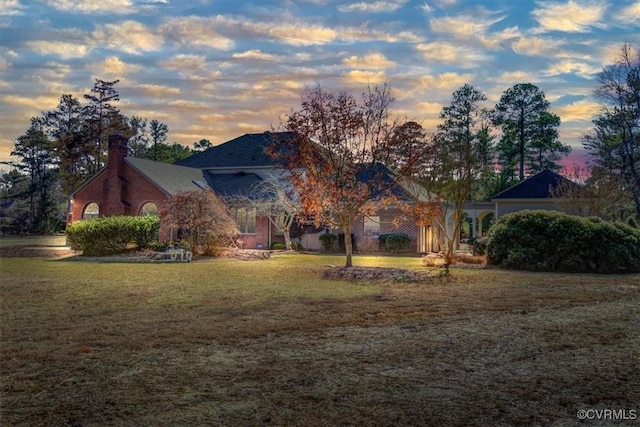 view of front facade with a yard and a chimney