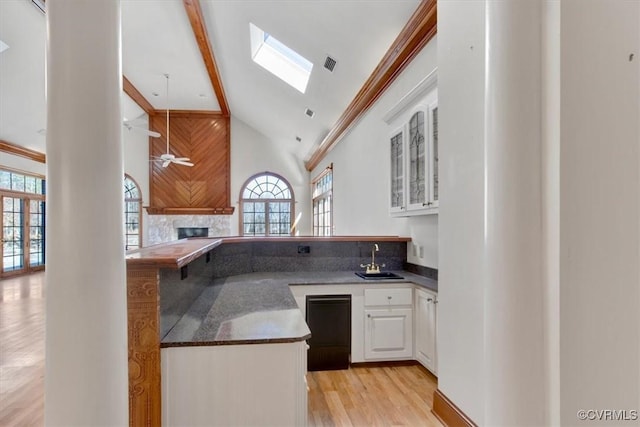 kitchen featuring a fireplace, visible vents, glass insert cabinets, white cabinetry, and a sink