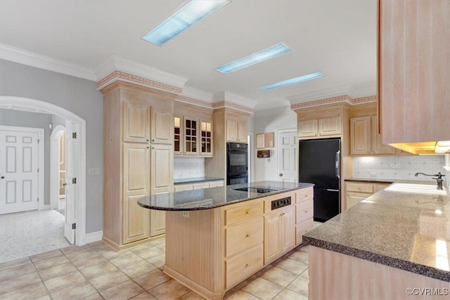 kitchen with a center island, arched walkways, light brown cabinets, a sink, and black appliances