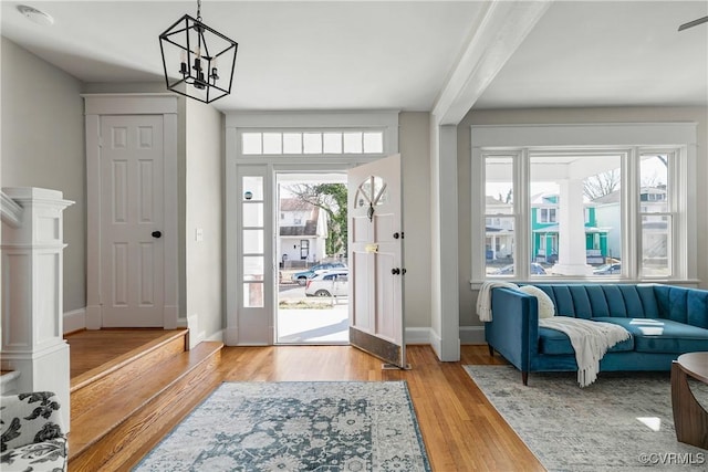 entryway featuring beamed ceiling, wood-type flooring, and a notable chandelier