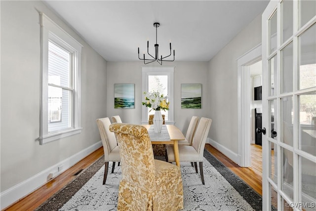 dining space with french doors, a chandelier, and light wood-type flooring