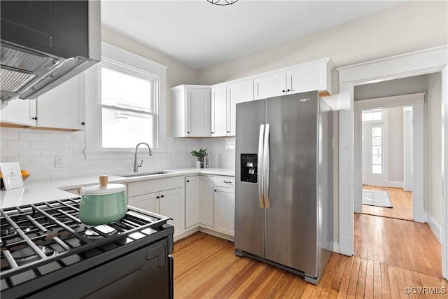 kitchen featuring stainless steel refrigerator with ice dispenser, light wood-type flooring, sink, and white cabinets