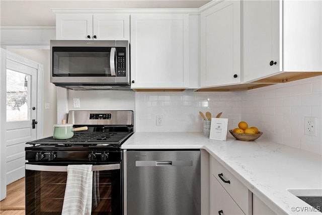 kitchen with light stone counters, appliances with stainless steel finishes, decorative backsplash, and white cabinets