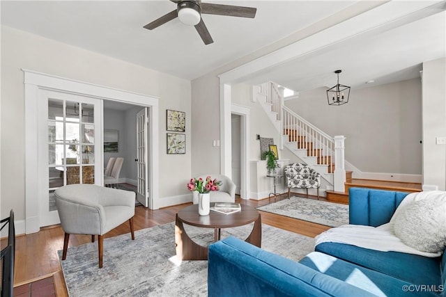 living room with hardwood / wood-style flooring and ceiling fan with notable chandelier