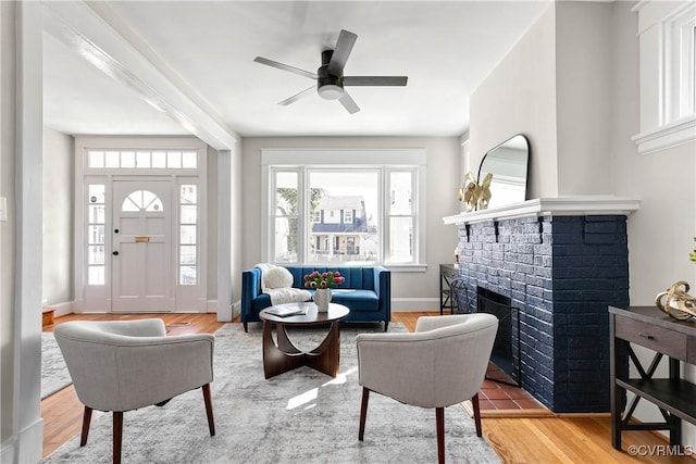 living room featuring ceiling fan, wood-type flooring, and a fireplace