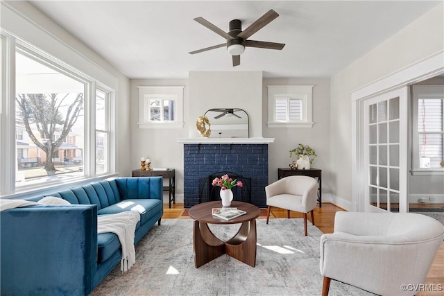 sitting room featuring ceiling fan, a fireplace, and light wood-type flooring