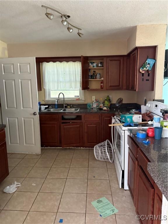 kitchen featuring sink, dark stone counters, white electric range oven, light tile patterned floors, and a textured ceiling