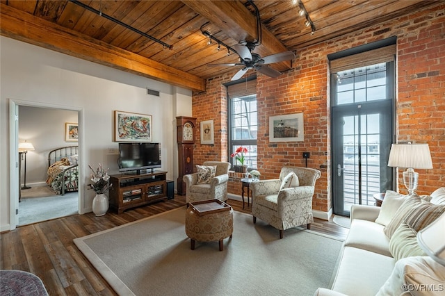 living room featuring beamed ceiling, brick wall, dark hardwood / wood-style flooring, and wooden ceiling